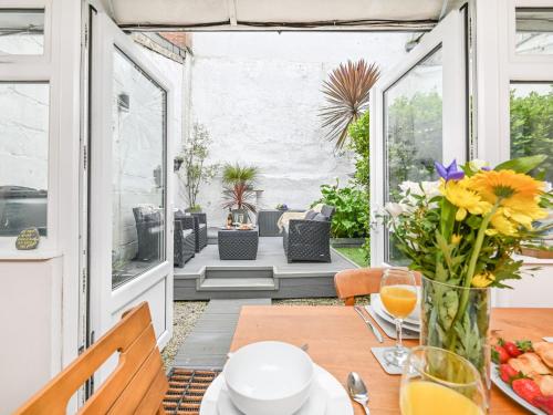 a patio with a table with a vase of flowers at Holiday Home Mariners Rest by Interhome in Mevagissey