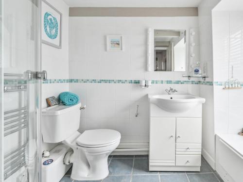 a white bathroom with a toilet and a sink at Holiday Home Mariners Rest by Interhome in Mevagissey