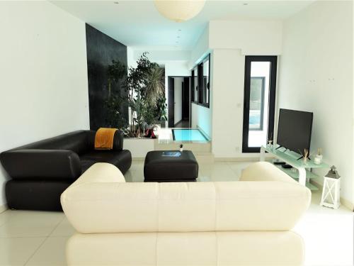 a living room with a white couch and a tv at Holiday Home L'Oustaloun by Interhome in Saint-Aygulf