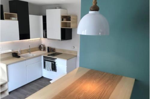 a kitchen with white cabinets and a wooden floor at Studio Tavernier - Oullins centre - Lyon in Oullins