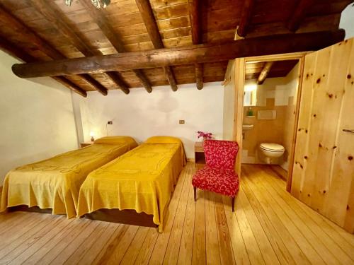 a bedroom with two beds and a red chair at Holiday Home Maria by Interhome in Verceia