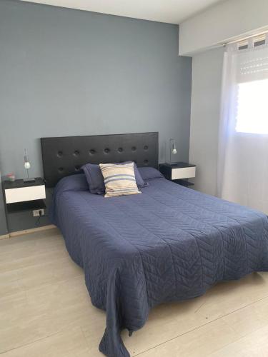 1 dormitorio con 1 cama grande y edredón azul en Bacota Flat en Bahía Blanca