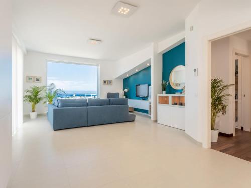 een woonkamer met een blauwe bank en een groot raam bij Apartment Quirat Superior by Interhome in Terrasini