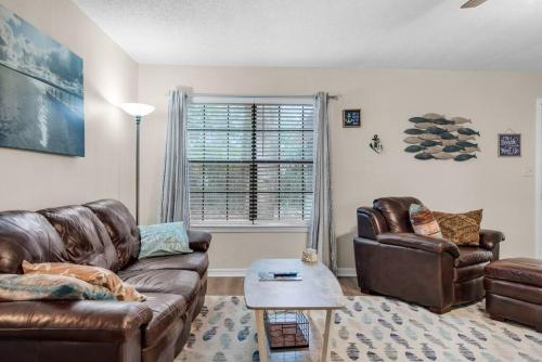 a living room with a leather couch and a table at Gulf Breeze - Canal front, Near Beach & Downtwn 3BR-2BT in Gulf Breeze