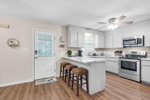 a kitchen with white cabinets and bar stools at Gulf Brz-Beaches-Dwntwn PNS-Pet Friendly-Canal in Gulf Breeze