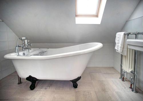 baño con bañera blanca y ventana en Dairy Three, en Embleton