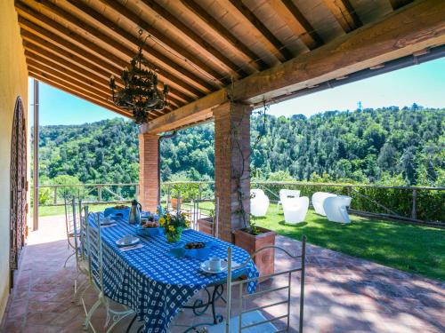 an outdoor dining room with a blue table and chairs at Villa Loris-2 by Interhome in Riparbella