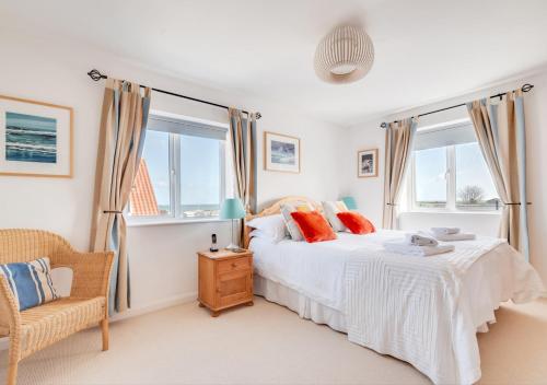 a bedroom with a bed and a chair and windows at Seafarers in Seahouses