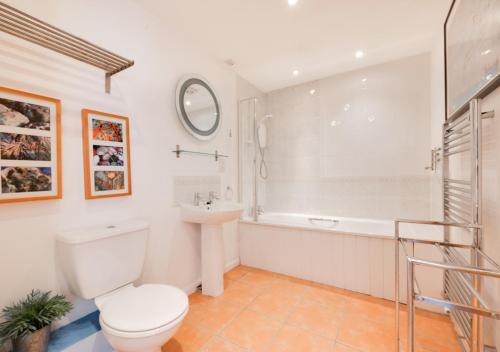 a bathroom with a toilet and a tub and a sink at Seafarers in Seahouses