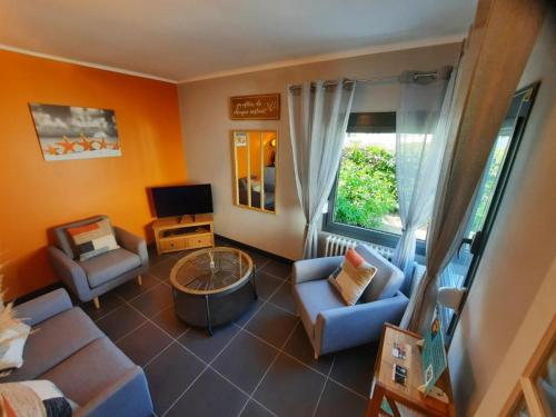 a living room with a couch and chairs and a tv at Le Marsouin in Sangatte