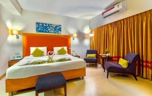 1 Schlafzimmer mit einem Bett, 2 Stühlen und einem Tisch in der Unterkunft Gis Select Banjara Hill in Hyderabad