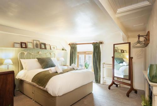 a bedroom with a large bed and a mirror at Chapel Cottage in Uffculme