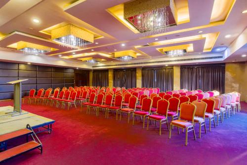a conference room with red chairs and a podium at Gis Select Banjara Hill in Hyderabad