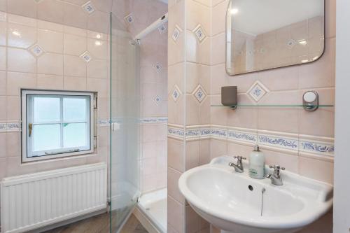 a bathroom with a sink and a shower and a mirror at Laundry Cottage in Pickmere