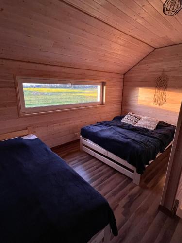 a bedroom with two beds in a wooden cabin at BALTICO Domki Letniskowe in Sarbinowo