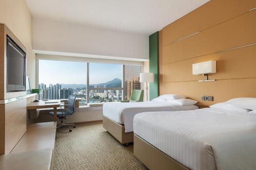 a hotel room with two beds and a desk and a window at Courtyard by Marriott Hong Kong Sha Tin in Hong Kong