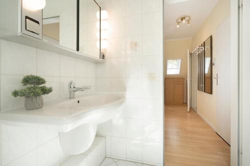 a white bathroom with a sink and a hallway at Haus Seepferdchen am Meer Appartement 7 in Timmendorfer Strand