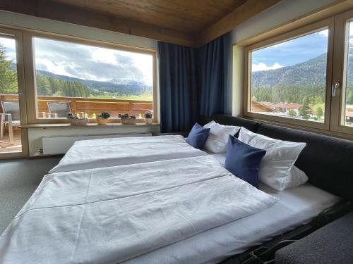 a bedroom with a large bed with two large windows at Chalet Cristall in Leutasch