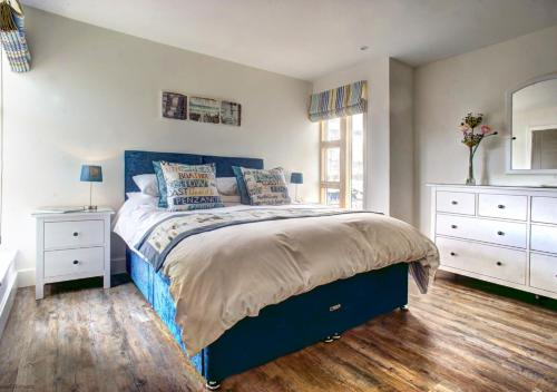 a bedroom with a blue bed with two white dressers at Quayside in Amble