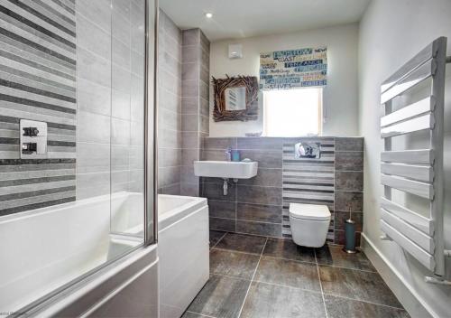 a bathroom with a tub and a toilet and a sink at Quayside in Amble