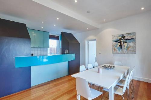 uma cozinha e sala de jantar com uma mesa branca e armários azuis em Large Two Bedroom Apartment with City Park and Bay views em Melbourne