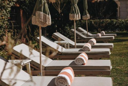 a row of lounge chairs with umbrellas on the grass at Parkhotel Mondschein, a Member of Design Hotels in Bolzano