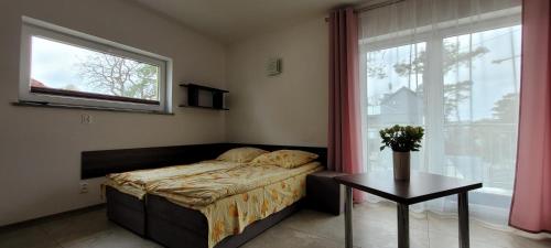a bedroom with a bed and a table and a window at Kama Pobierowo 2 in Pobierowo