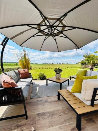 a large umbrella over a patio with couches and tables at L'échappée Belle by J&J Durbuy Area in Clavier