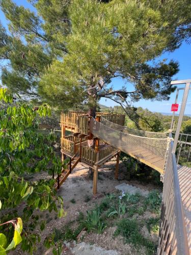 a tree house with a hammock under a tree at DOMAINE MAXXIM in Clermont-lʼHérault