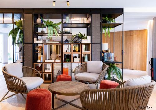 a lobby with chairs and tables and a book shelf at Paxton Paris MLV in Ferrières-en-Brie