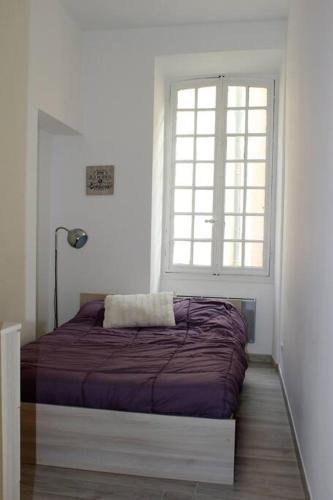 un lit dans une chambre blanche avec une fenêtre dans l'établissement appartement Menton au coeur de la vieille ville, à Menton