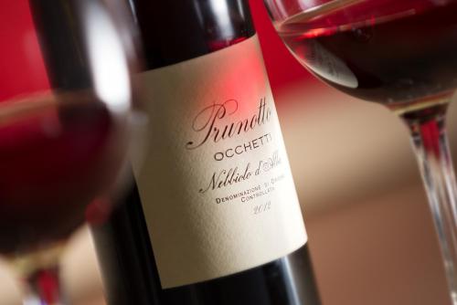 una bottiglia di vino rosso accanto a un bicchiere di vino di Dimora in Alba ad Alba