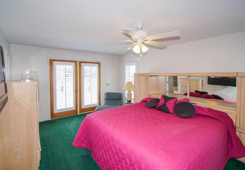 a bedroom with a pink bed with a ceiling fan at Seascape in Myrtle Beach