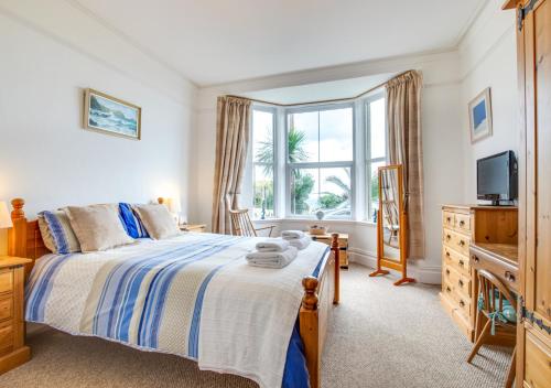 a bedroom with a bed and a tv and a window at An Marghty 4a Carthew Terrace in St Ives