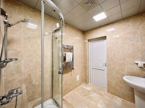 y baño con ducha acristalada y lavamanos. en Deluxe Park Qusar Resort & Spa Hotel, en Qusar