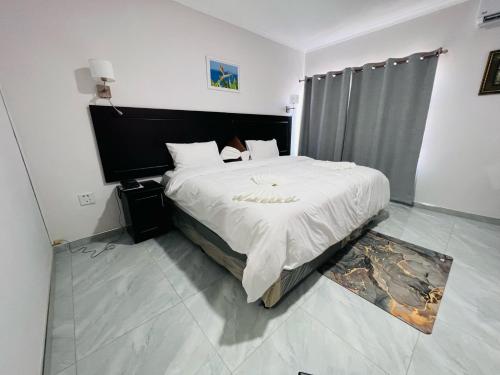 una camera da letto con un grande letto con lenzuola bianche di Maun Nest Hotel a Maun