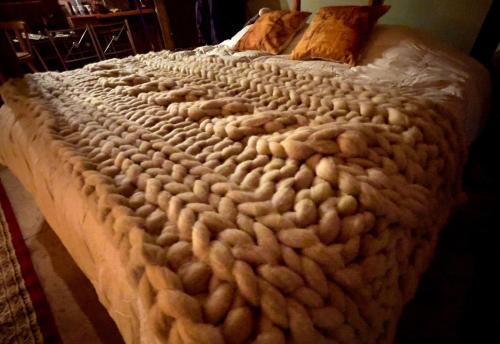 Una cama grande con una manta de punto. en Explore - Cozzy Cabin Located in Duhatao, Chiloe Island, Patagonia, Chile, en Ancud