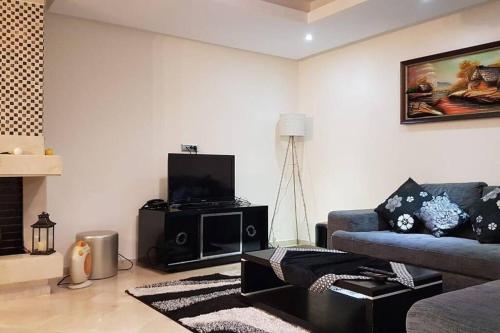 sala de estar con sofá y TV en Appartement-résidence prestigia plage des Nations, en Rabat