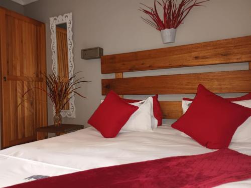 een slaapkamer met een bed met rode en witte kussens bij Eagle Creek Resorts Sabie in Sabie
