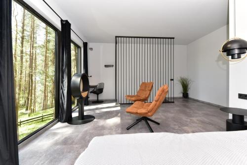 a bedroom with a bed and a desk and chairs at Premium Forest Bungalow with HOT TUB in Ažuluokesa