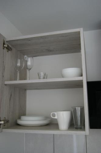 a kitchen shelf with plates and bowls on it at Kama Pobierowo 2 in Pobierowo