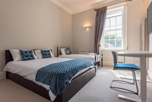 a bedroom with two beds and a table and a desk at Luxury flat next to town centre Long-stay discount in Reading