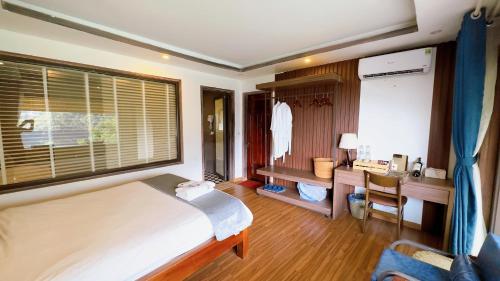 a bedroom with a bed and a desk and a window at Sapa Eco Villas & Spa in Sa Pa
