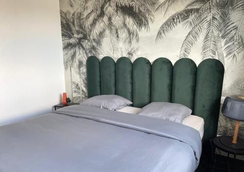 une chambre avec un grand lit avec une tête de lit verte dans l'établissement Villa contemporaine avec piscine chauffée proche des plages, à Sauvian