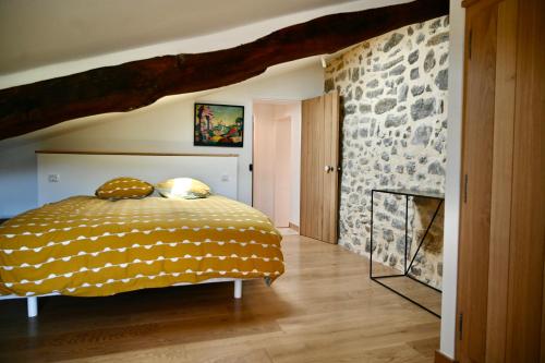 a bedroom with a bed and a stone wall at Mas de Chassole Les Gîtes de l'Aurore in Ongles