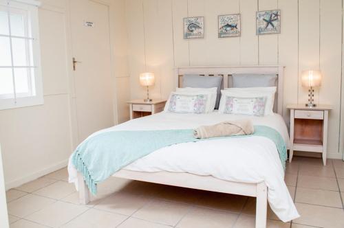 a white bedroom with a large white bed with pillows at Barefoot Lodge, Mossel Bay in Mossel Bay