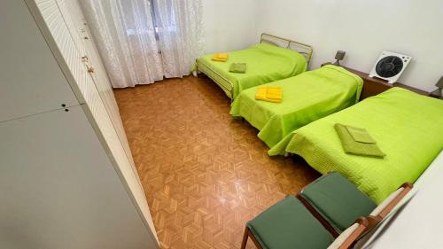 two beds in a room with green sheets at da Lilia in Salute&Bellezza in Monfalcone