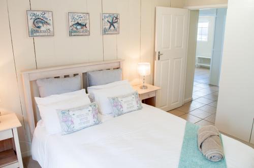 a bedroom with a white bed with pillows on it at Barefoot Lodge, Mossel Bay in Mossel Bay