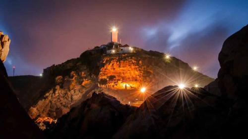 a mountain with a lighthouse on top of it at night at Barefoot Lodge, Mossel Bay in Mossel Bay