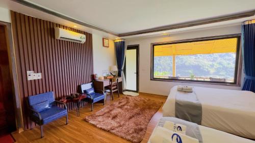 a bedroom with a bed and chairs and a large window at Sapa Eco Villas & Spa in Sa Pa